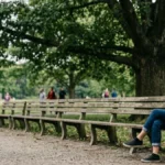 Seseorang duduk sendirian menjaga jarak di bangku taman menggambarkan makna avoidant artinya cenderung menghindari kedekatan emosional